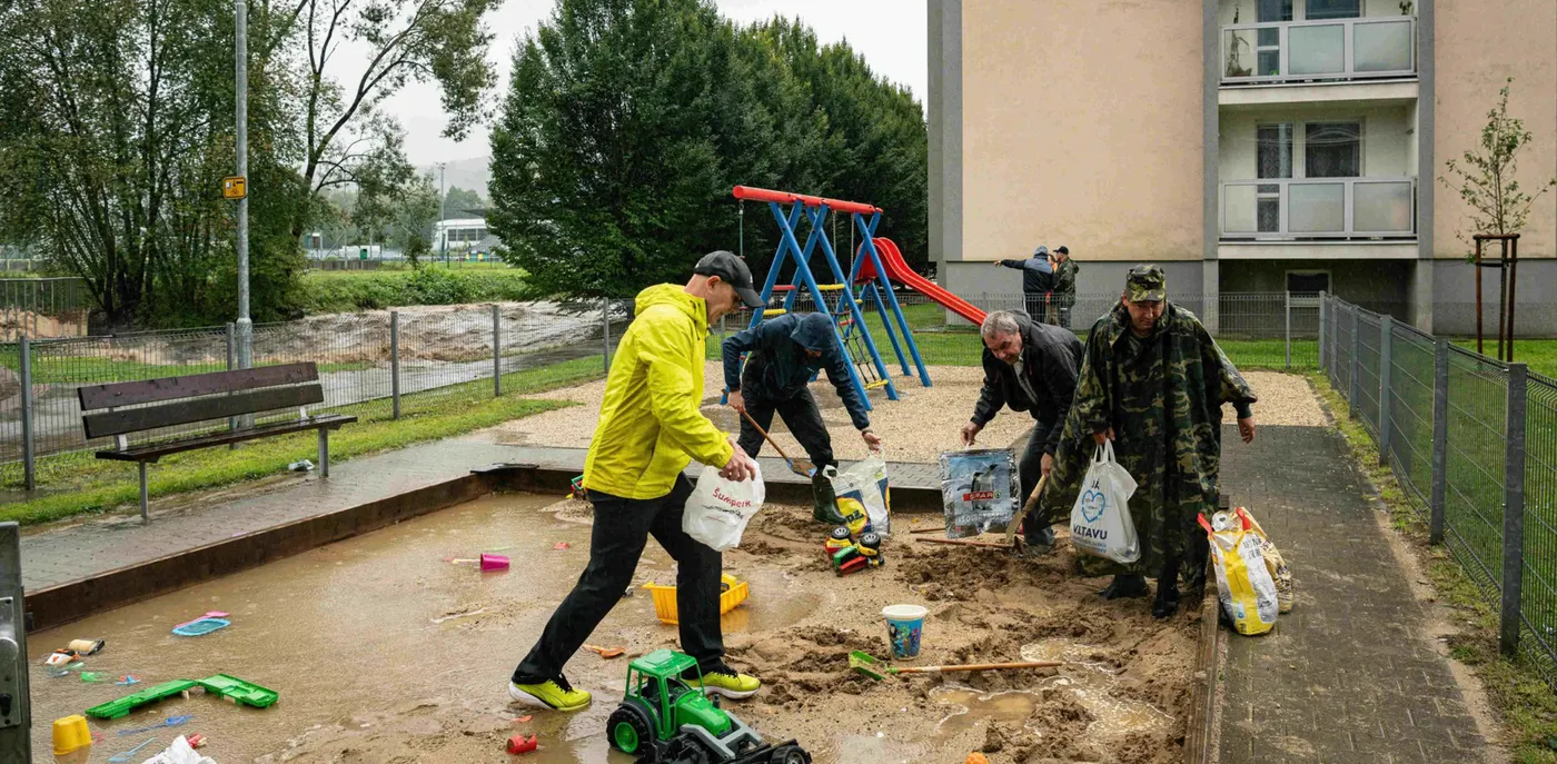 Dobrovolníci na sídlišti plní tašky pískem z dětského pískoviště, aby zadrželi povodeň